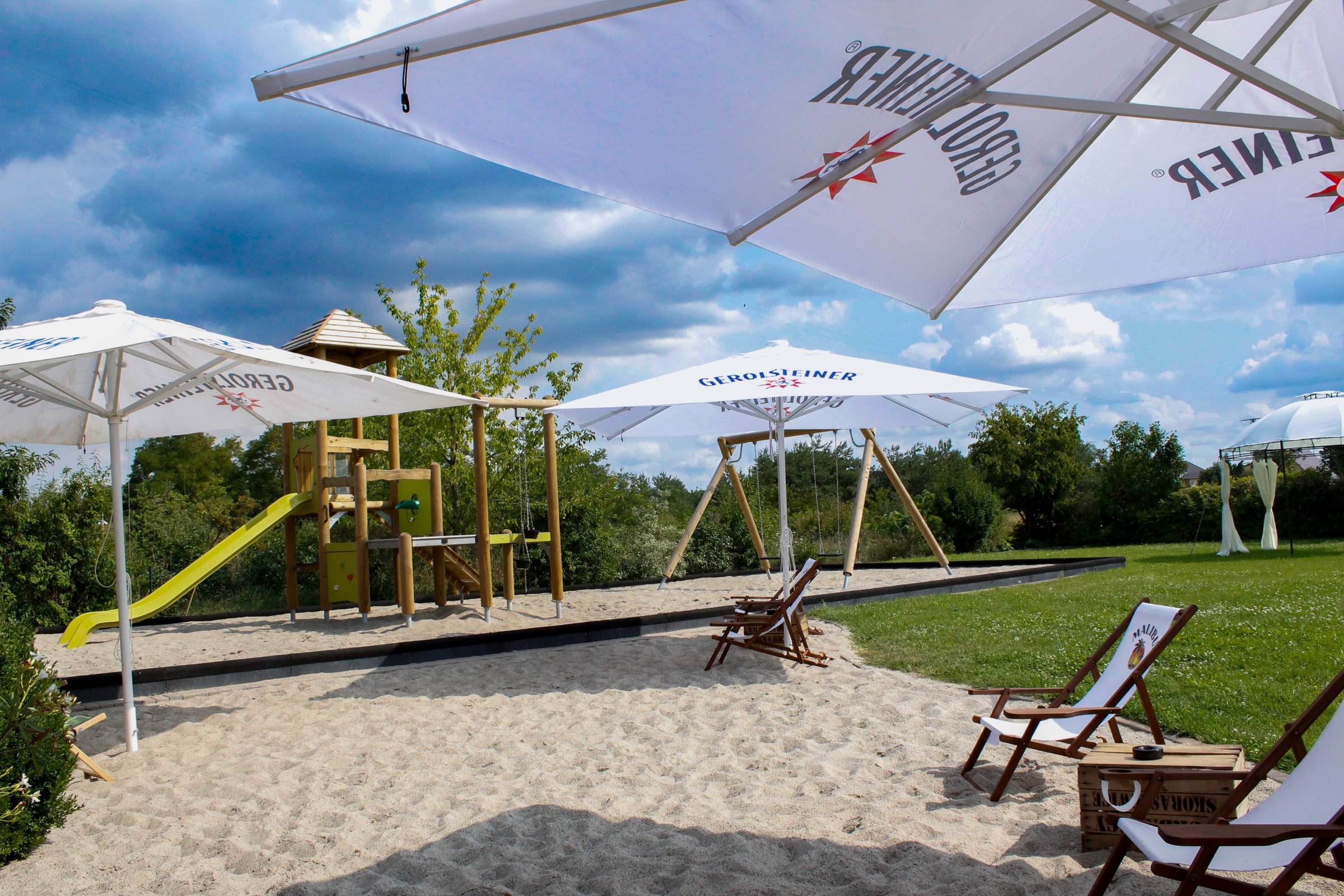 Strandbereich des Landhotels mit Sandstrand, Sonnenliegen und Spielplatz